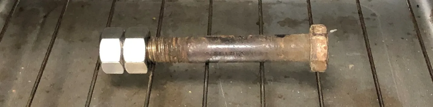 A large bolt being heated in an oven prior to using it to insert two steel hex nuts